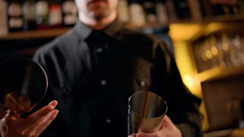 Close-up of a bartender in a dim bar assembling stainless steel cocktail shakers Stock Footage 318640994