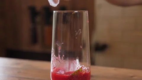 Close-up of a bartender in gloves putting ice cubes in a glass with berry juice. Stock Footage 345132423