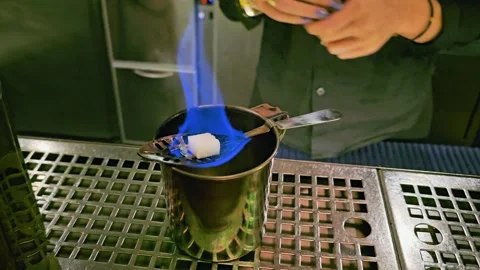 Close-up of bartender igniting a sugar cube over a metal cup, with blue flame Stock Footage 339846908
