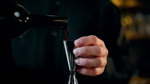 Close-up of bartender measuring liquor with a jigger and pouring into a Stock Footage 318649401