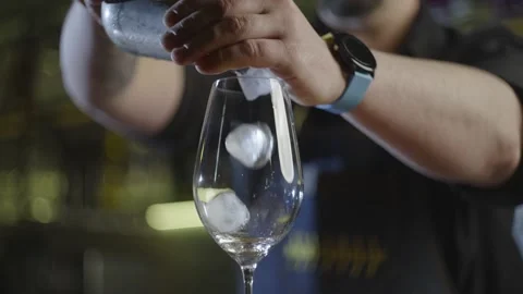 Close-up of a bartender pouring ice into a cocktail glass. Stock Footage 230645937