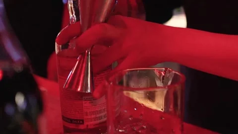 Close Up of Bartender Pouring Spirits with Jigger Under Red Light Stock Footage 327346628