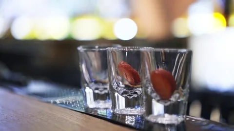 Close up of a bartender pouring vodka into cocktail glasses with strawberry 스톡 동영상 79360279