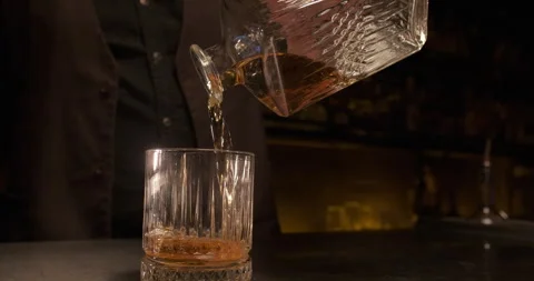 Close-up bartender pouring whiskey from the decanter. Enjoy alcoholic drink at 스톡 동영상 258429912