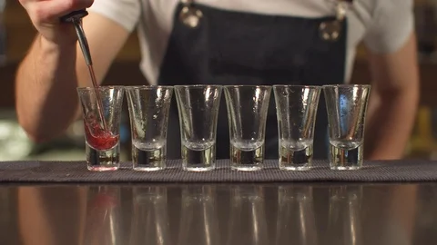 Close up, bartender pours alcohol in shot glasses one by one Stock Footage 123685431
