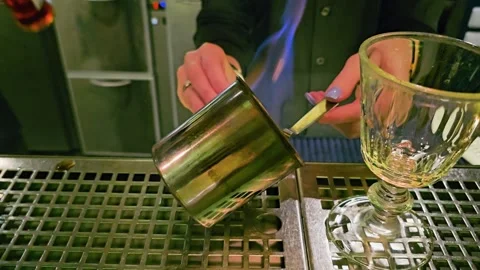 Close-up of a bartender preparing a flaming cocktail at a dim bar, with blue Stock Footage 339848971