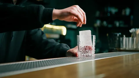 Close up of bartender putting crystal ice cubes in glass while preparing Stock Footage 240438496