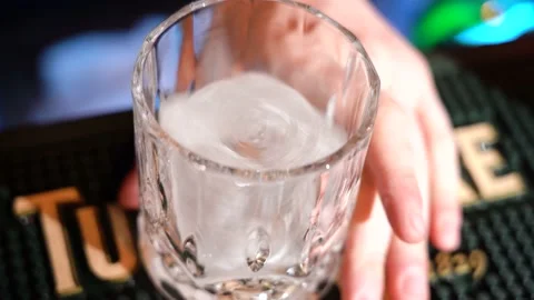 Close up bartender is putting professional crystal ice cubes in glass Stock Footage