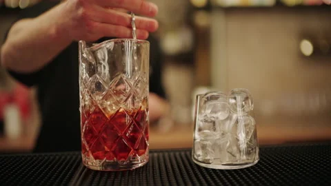 Close up of a bartender stirring a cocktail with ice in a crystal mixing glass Stock Footage 332664533
