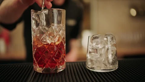 Close up of a bartender stirring a cocktail with ice in a crystal mixing glass Stock Footage 332664830