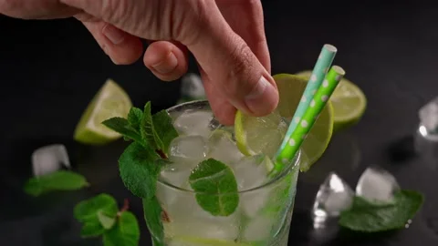 A close-up of a bartender's Hand Decorating with a Slice of Lime Mojito Cocktail Stock-Footage 237436476