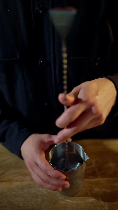 Close-up of a bartenders hands using a spiral bar spoon to stir ice in a Stock-Footage 318539392