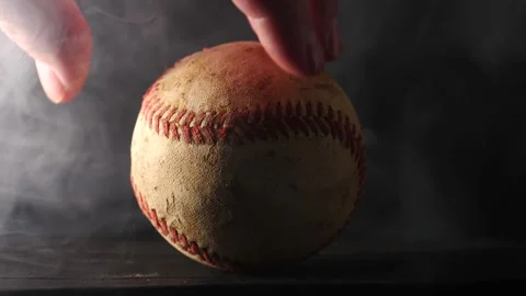 Close up of baseball being spun in slow motion by hand smoke and swirling Stock Footage 206835961