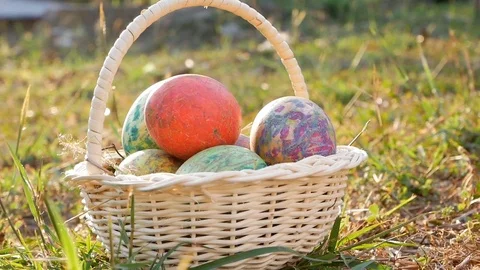 Close-up of basket with colourful a easter eggs on grass in sunshine Stock Footage 84579202