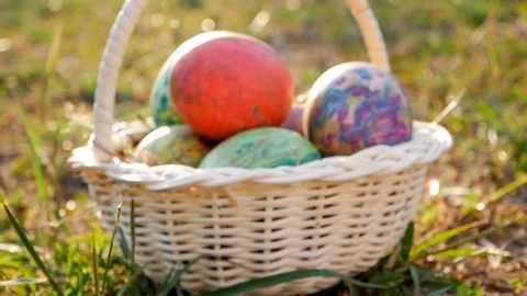 Close-up of basket with colourful a easter eggs on grass in sunshine Stock Footage 84579225