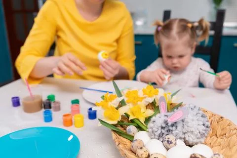 Close up of basket with Easter eggs and toy-rabbit. Defocused teacher and tod Stock Photos