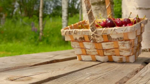 Close up of a basket full of ripe cherries falling on a wooden table Stock Footage 126158918
