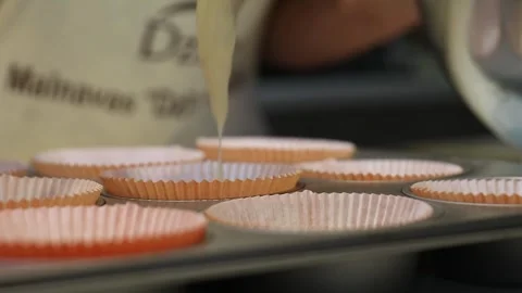 Close Up of Batter Being Spoon Filled Into Pink Cupcake Liners Stock Footage 298167321