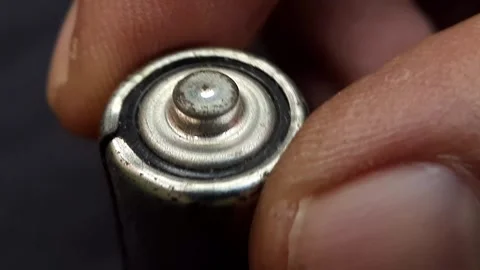 Close-up of a battery positive terminal held by fingers Stock Footage 310464939