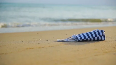 Close-up beach bag lie on sandy shore against blurred sea with sea waves Video stock 93110762