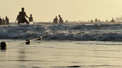 Close up of Beach Buoy on Rope at sandy Shoreline and people silhouettes in the Vidéo 342472055