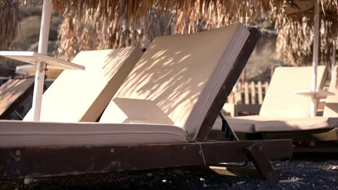 Close up of beach chairs with straw beach umbrellas in warm sunshine Vidéo 265939944