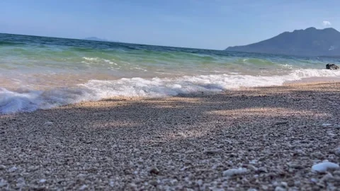 Close-Up Beach Waves With Mountain Coastline Background Stock Footage 334986190