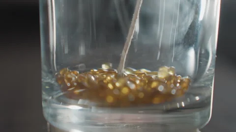 Close Up of Beads Falling into Glass Cup with Wick for Creative Decoration Stock-Footage 307985688