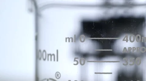 Close up of a beaker with a moving robot in the background Stock Footage 64353176