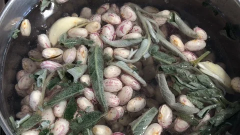 Close up of beans cooked with green sage and water in a metal pot. Stock-Footage 86131875