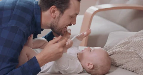Close up of bearded and mustashed father is kneeling by the baby lying on the 库存影片 140172409