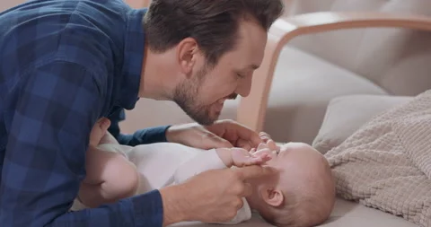 Close up of bearded and mustashed father is kneeling by the baby lying on the 動画素材 140172985