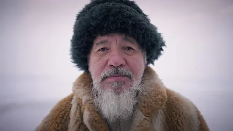Close-up bearded face of old indigenous man looking at camera standing outdoors Video stock 163746959