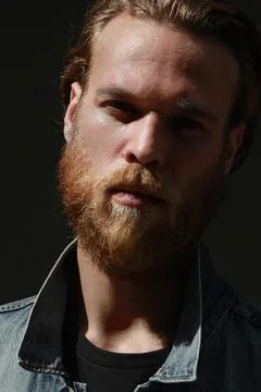 Close-up of bearded hipster man posing outdoor wears denim jacket. Vertical. 스톡 사진