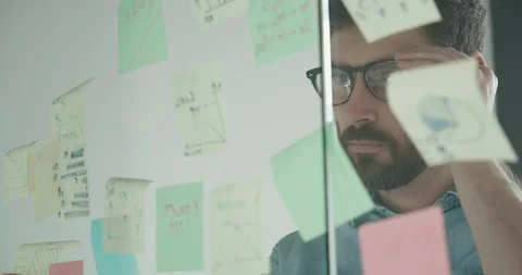 Close up of Bearded IT Worker standing by Glass Board with Multicolor Papers. Stock Footage 124287424