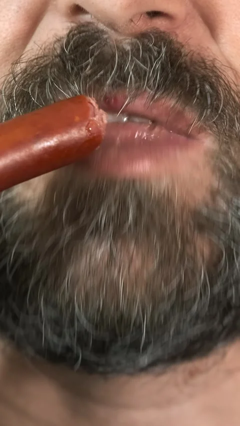 Close-up, bearded man eats, fast food, smoked sausage. Stock Footage 285706388