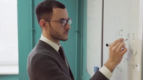 Close-up of a bearded man with glasses writing on a white board Stock Footage 85039926