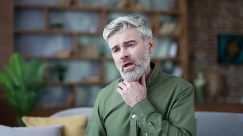 Close-up of bearded man with gray hair touching his throat in pain. Senior male  Stock Footage 328706137