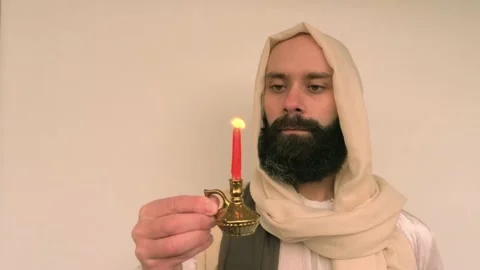 Close-up bearded man in image of Savior holding burning candle, Jesus Chris.. Stock Footage 234198902
