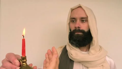 Close-up bearded man in image of Savior holding burning candle, Jesus Chris.. Stock Footage 236995076