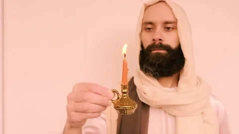 Close-up bearded man in image of Savior holding burning candle, Jesus Chris.. Stock Footage 244069028