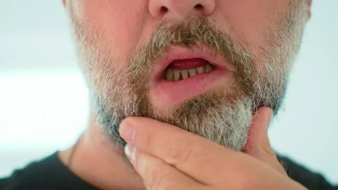 Close up bearded man touching gray beard with fingers during morning grooming in Stock Footage 345125752