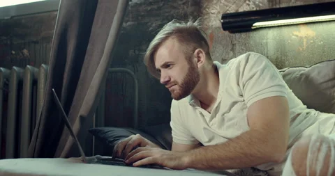 A close-up of a bearded man typing on the Laptop sitting in his comfortable bed Stock Footage 135239035
