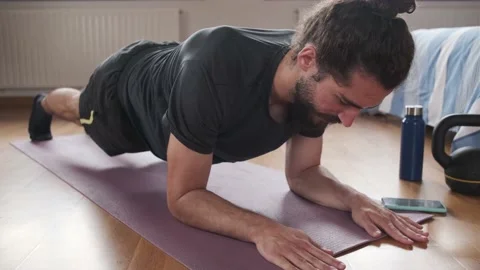 Close-up of a bearded man using his mobile phone to do planks at home. Stock Footage 158487879