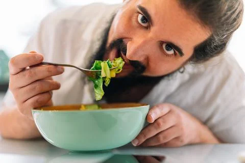 Close-up of a bearded young man eating a salad Stock Photos