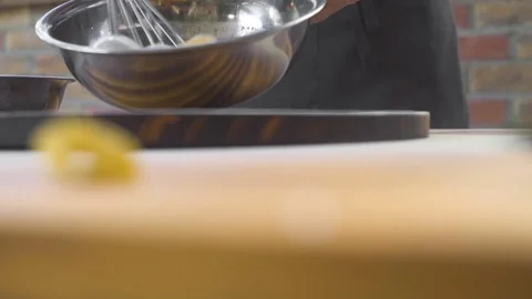 Close up beating eggs with kitchen whisk in metal bowl for morning omelette or Stock Footage 108071584