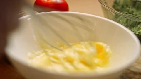 Close up beating eggs with kitchen whisk in metal bowl for morning omelette or Stock Footage 156722659