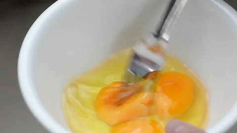 Close up beating eggs in a white bowl Stock Footage 112536542