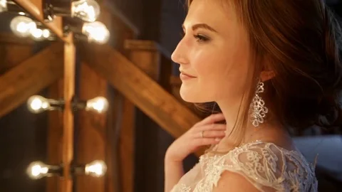 Close-up of beautiful bride stands in front of a mirror with lights in a loft Stock Footage 69827855