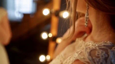 Close-up of beautiful bride stands in front of a mirror with lights in a loft Stock Footage 69827869